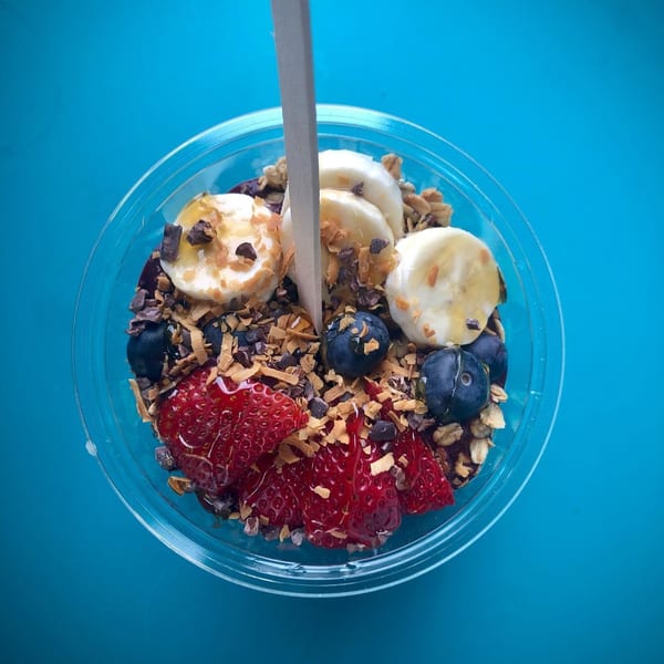 Overhead view of a Gansett Poke bowl with strawberries, blueberries, bananas, granola, and chocolate shavings.
