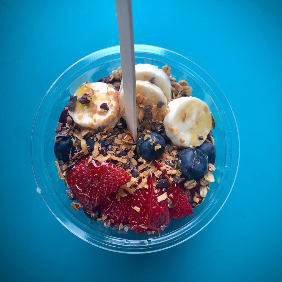 Overhead view of a Gansett Poke bowl with strawberries, blueberries, bananas, granola, and chocolate shavings.