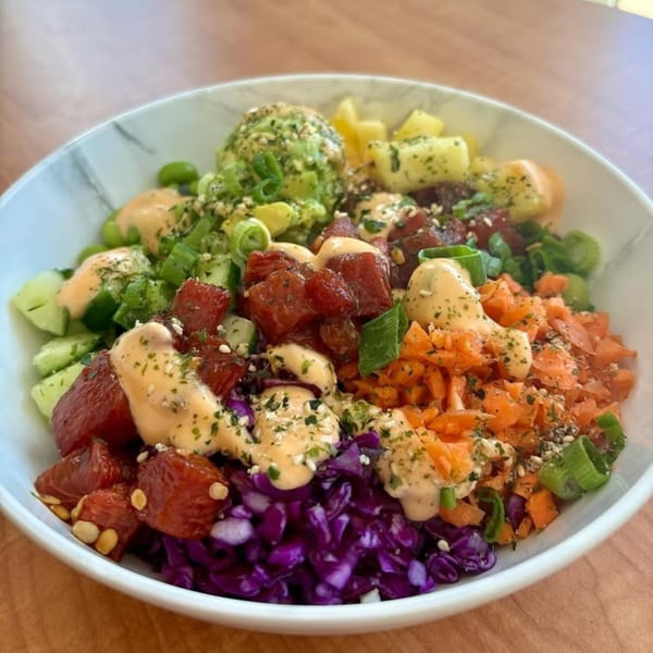 Close-up of a colorful Gansett Poke bowl with tuna, avocado, pineapple, carrots, and purple cabbage.